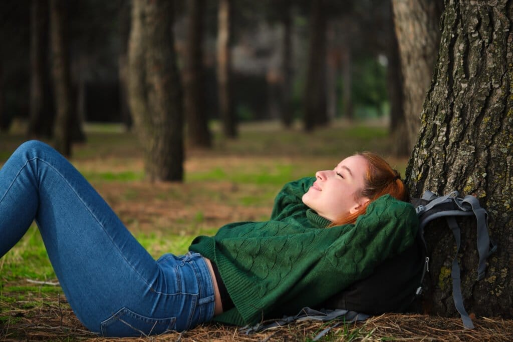 Redhead young woman resting lying under tree in forest Acceptance Path importane of rest