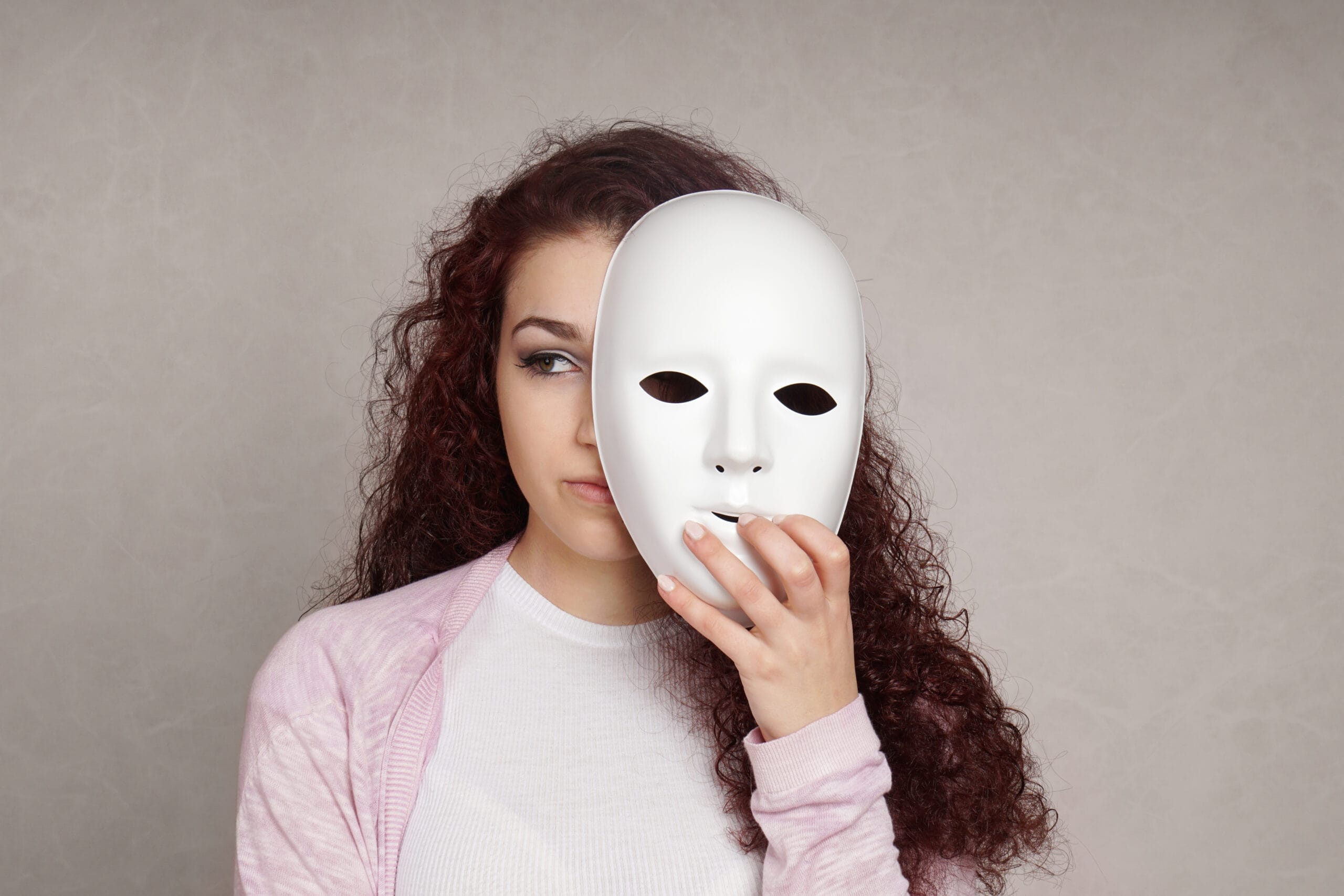 A woman holding a mask symbolizes identity beyond a borderline personality disorder test This represents authentic living for residents in Panther Creek and The Woodlands