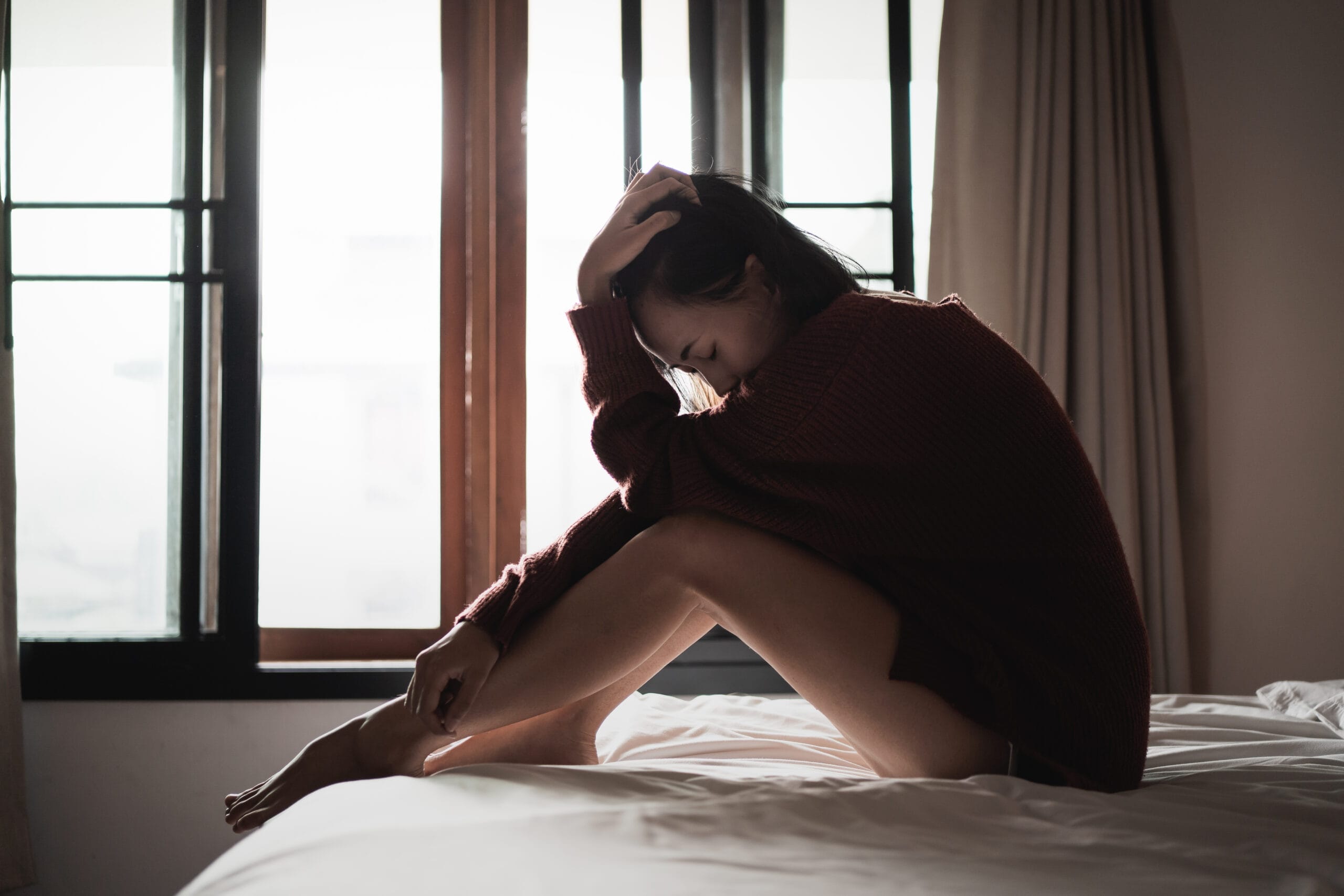 womansufferingfromdepressionsittingonthebed20260111094949utc Acceptance Path Counseling Woman experiencing the physical symptoms of the body's trauma response, demonstrating why learning how to heal from trauma requires more than cognitive insight