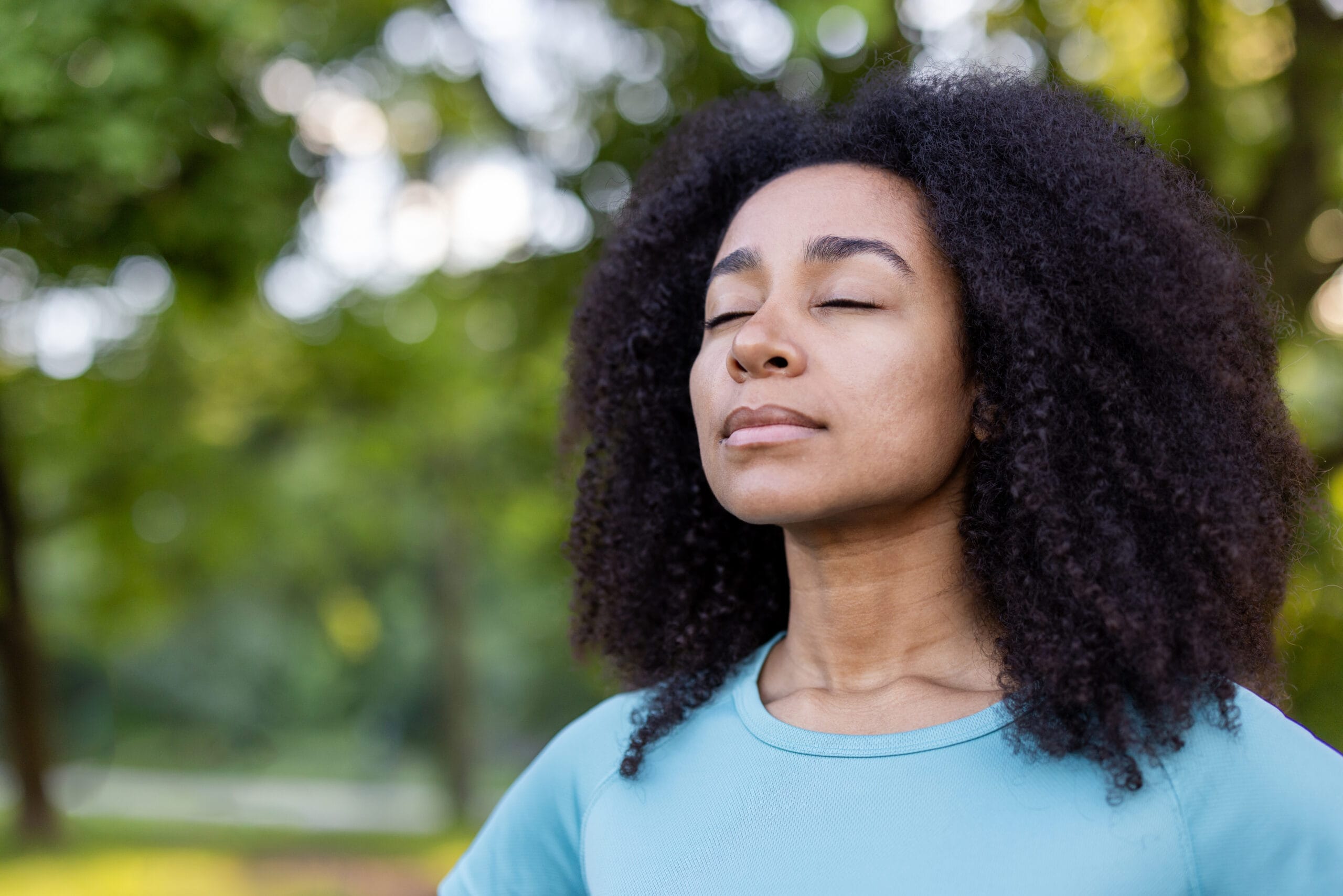 A woman practicing mindfulness meditation outdoors in a park representing practical exercises for mental clarity and managing intrusive thoughts