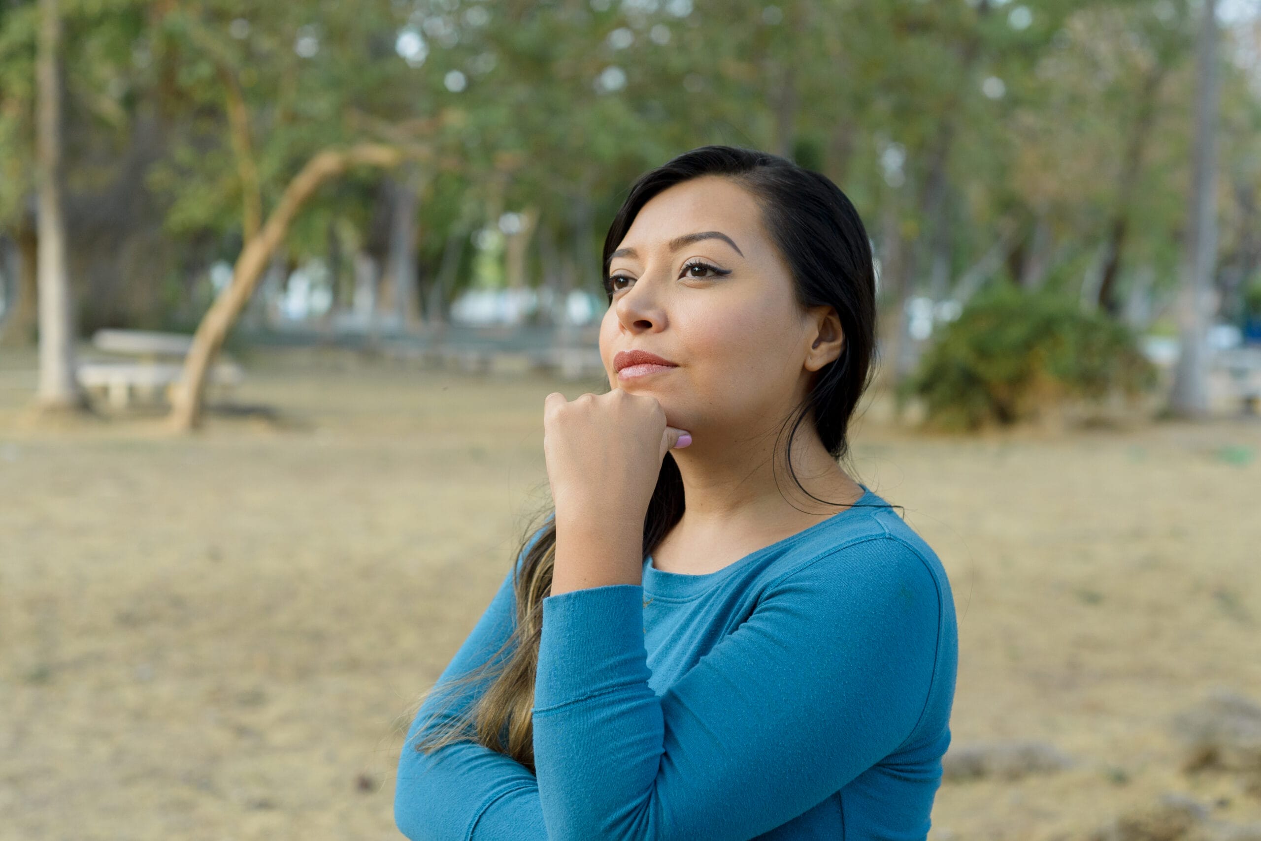 A woman looking thoughtfully into the distance in a natural setting representing recovery and reclaiming a value driven life after managing intrusive thoughts in The Woodlands
